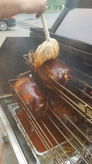 Mopping pork butts on spit roaster baskets – a tantalizing step in the journey to barbecue perfection