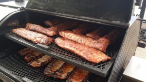 Fifteen racks of succulent ribs grilling on the barbecue, a feast for the senses