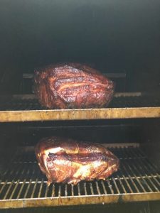 Two pork butts smoking on the grill, promising a savory and aromatic barbecue experience
