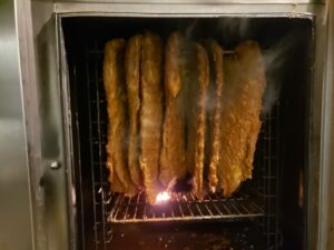 Smoker filled with racks of succulent ribs cooking to perfection.