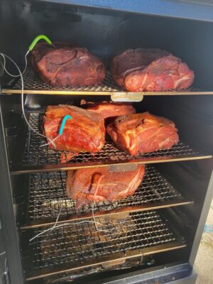 Eight pork butts arranged in a large cabinet smoker – a smoky spectacle ready for slow and savory perfection