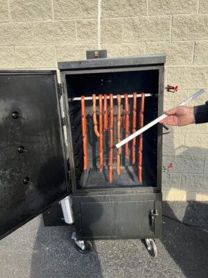 Links of hot dogs hanging in a smoker, ready for the smoky infusion of flavor