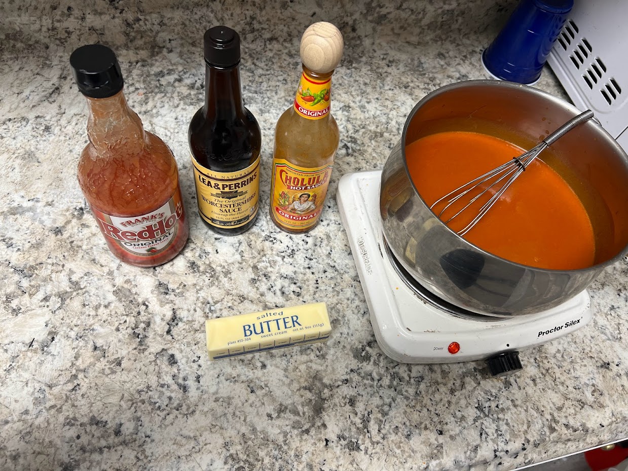 A variety of ingredients laid out on a countertop, including hot sauce, butter, and Worcestershire sauce